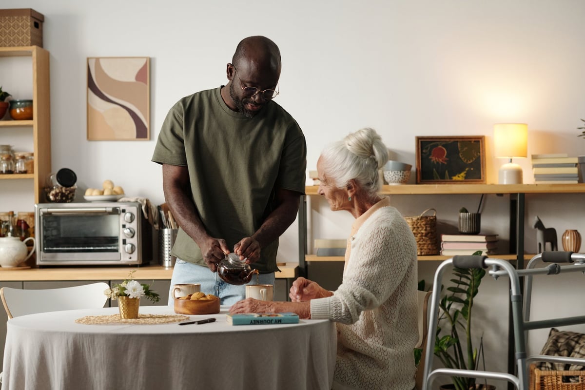 An African American companion caregiver sharing a warm moment over coffee with a Veteran at home